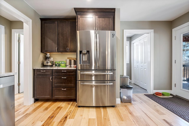 kitchen featuring dark brown cabinetry, baseboards, light countertops, stainless steel refrigerator with ice dispenser, and light wood finished floors