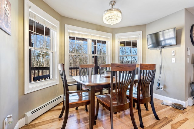 dining area with light wood-type flooring, baseboards, a baseboard heating unit, and a chandelier