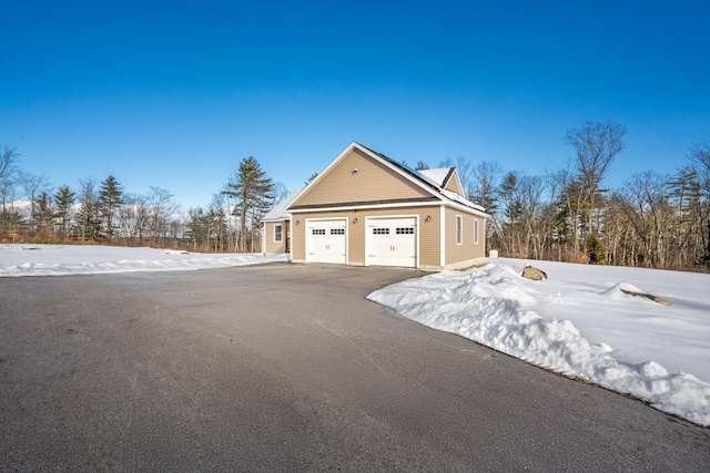 view of snow covered exterior with a garage and solar panels