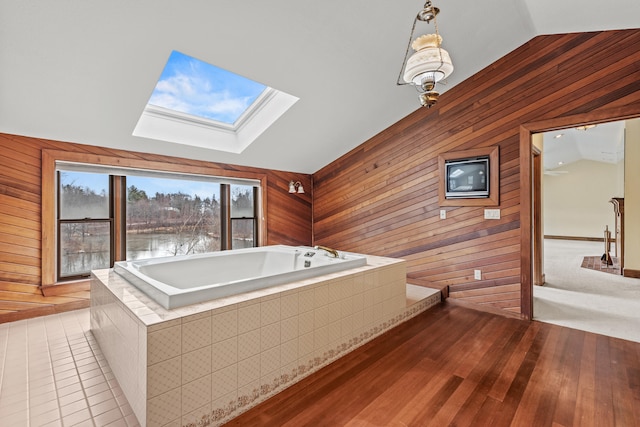 bathroom with lofted ceiling with skylight, hardwood / wood-style floors, and wood walls