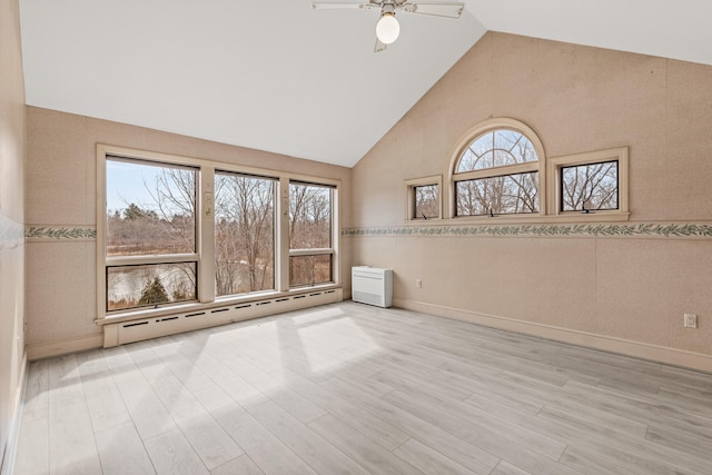 spare room featuring baseboard heating, wood finished floors, high vaulted ceiling, and a ceiling fan