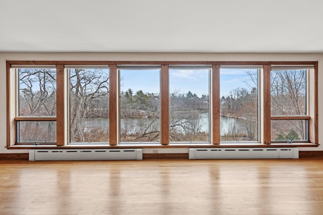 interior space featuring a baseboard heating unit, wood finished floors, and a water view