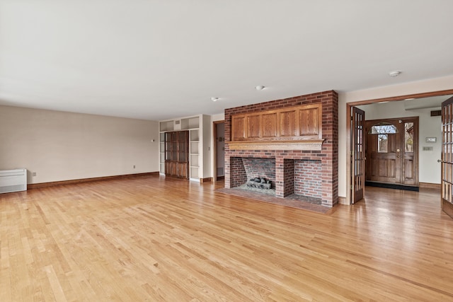 unfurnished living room with baseboards, light wood-type flooring, and a fireplace