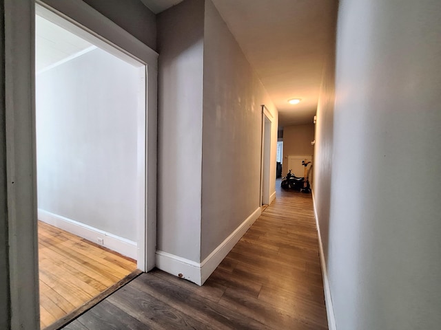 hallway with dark wood finished floors and baseboards