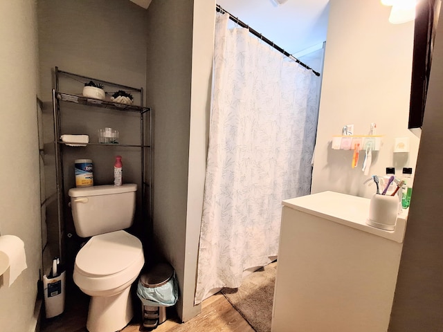 full bathroom with a shower with shower curtain, wood finished floors, and toilet