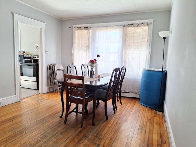 dining room with hardwood / wood-style flooring, baseboards, and ornamental molding