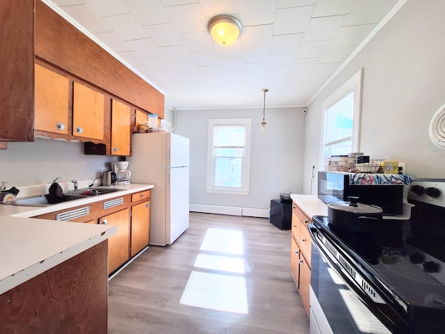 kitchen with a wealth of natural light, light countertops, crown molding, and freestanding refrigerator