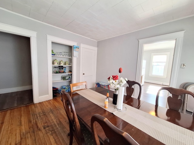 dining space with built in features, ornamental molding, baseboards, and hardwood / wood-style flooring