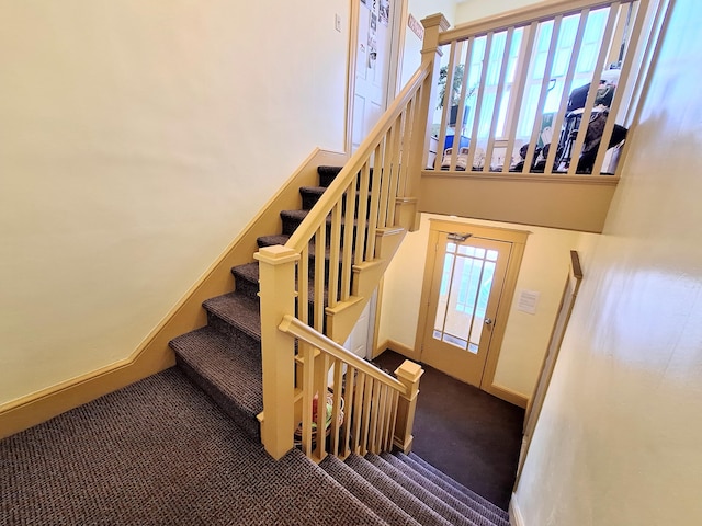 stairway with carpet, a high ceiling, and baseboards