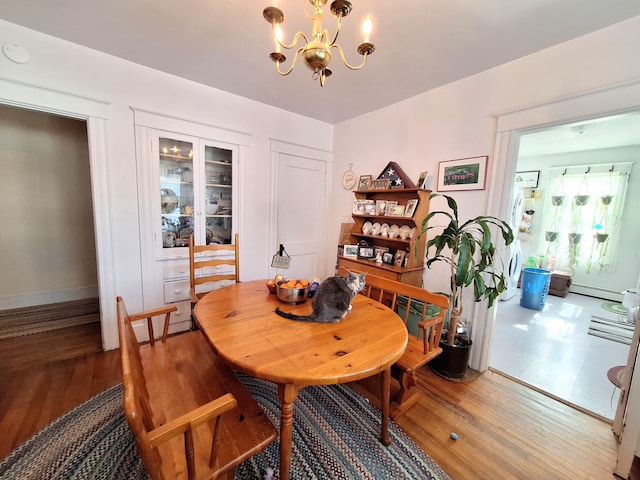 dining room featuring a baseboard heating unit, an inviting chandelier, and wood finished floors