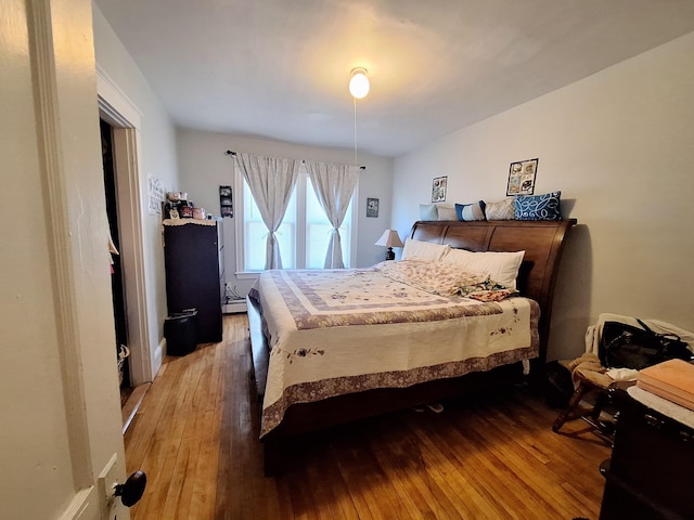 bedroom featuring a baseboard heating unit and light wood finished floors