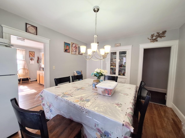 dining space featuring baseboards, wood finished floors, and an inviting chandelier