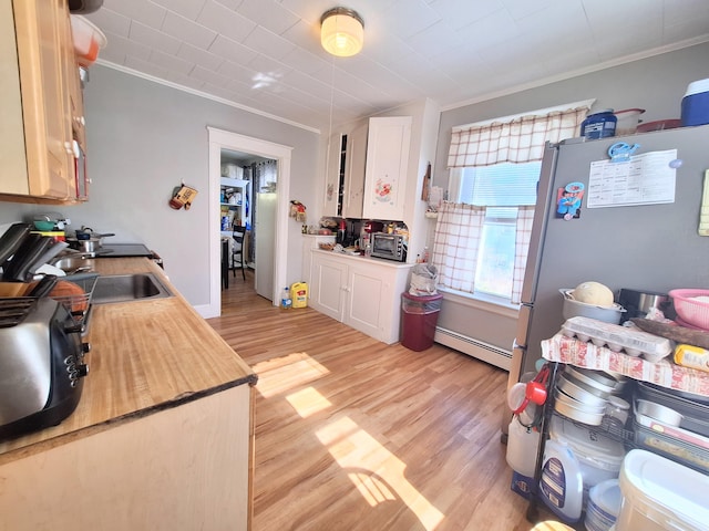 kitchen featuring light wood finished floors, a baseboard heating unit, crown molding, and freestanding refrigerator