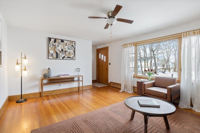 living area featuring baseboards, baseboard heating, wood finished floors, and a healthy amount of sunlight