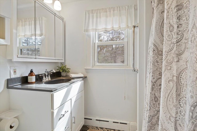 full bathroom with a healthy amount of sunlight, baseboard heating, and vanity