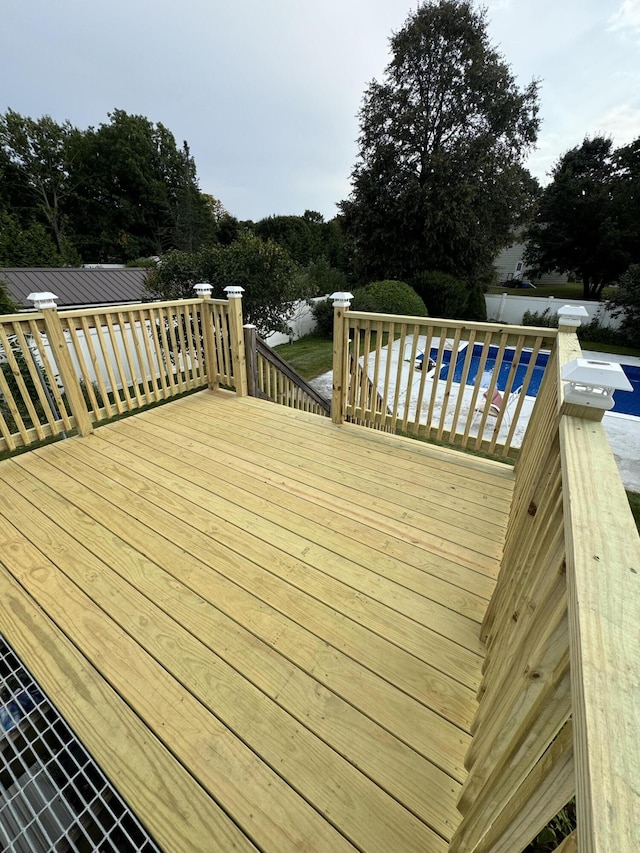 wooden deck with an outdoor pool and fence