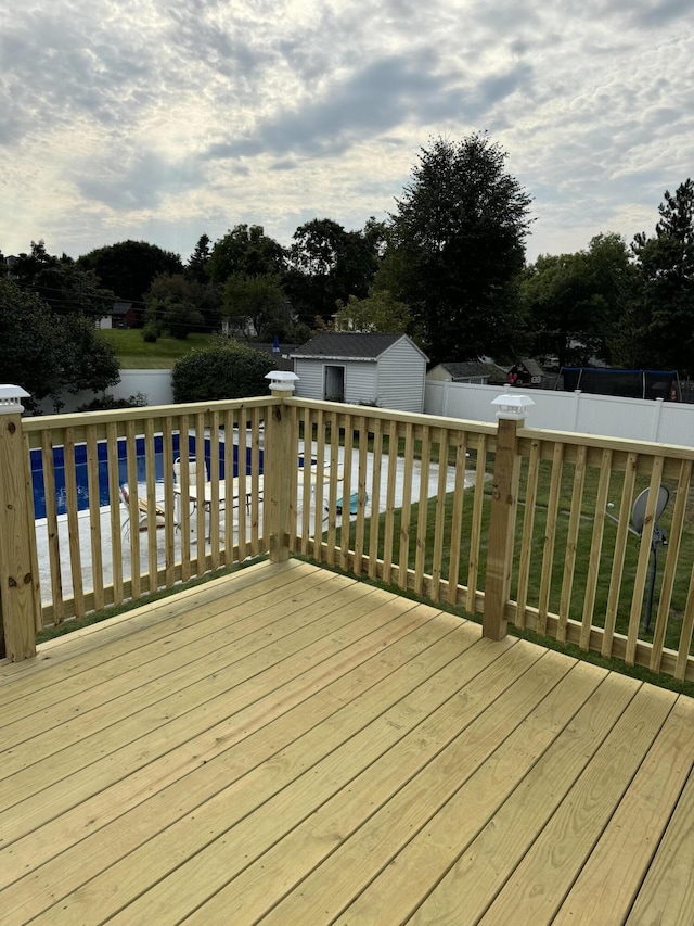 wooden terrace featuring a water view, a lawn, a fenced backyard, an outdoor pool, and an outdoor structure