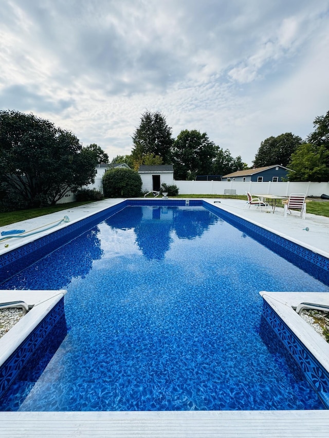 view of swimming pool featuring a fenced in pool, a fenced backyard, an outbuilding, a storage unit, and a patio area