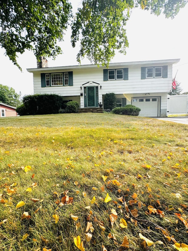 raised ranch with an attached garage and a front lawn