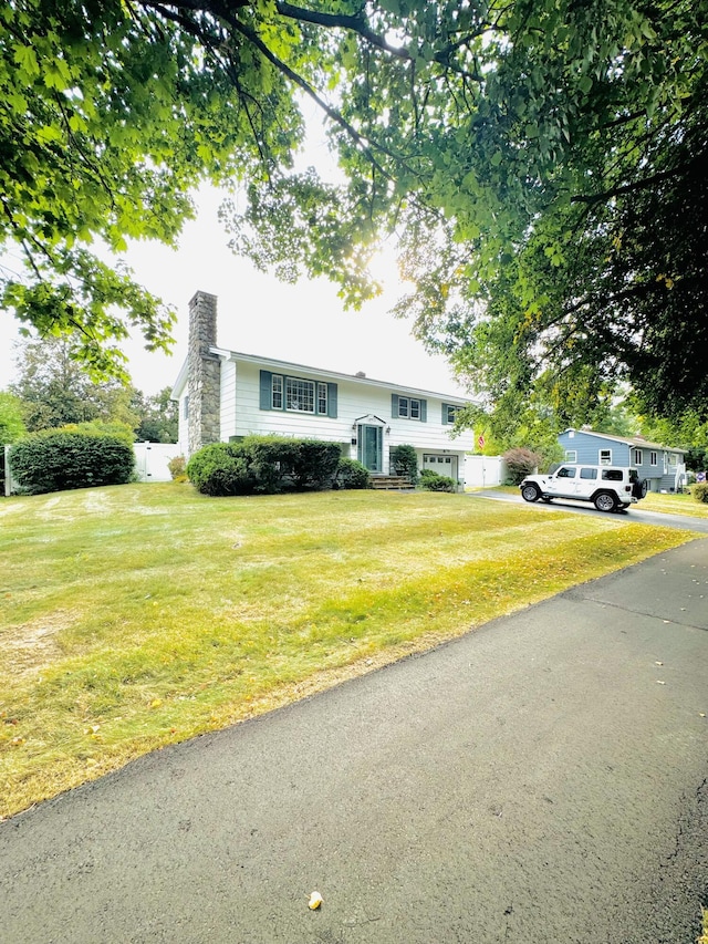 raised ranch featuring a chimney and a front lawn