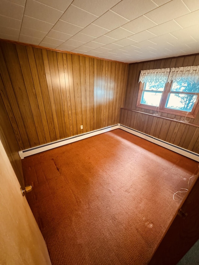 spare room with carpet, wood walls, and a baseboard radiator