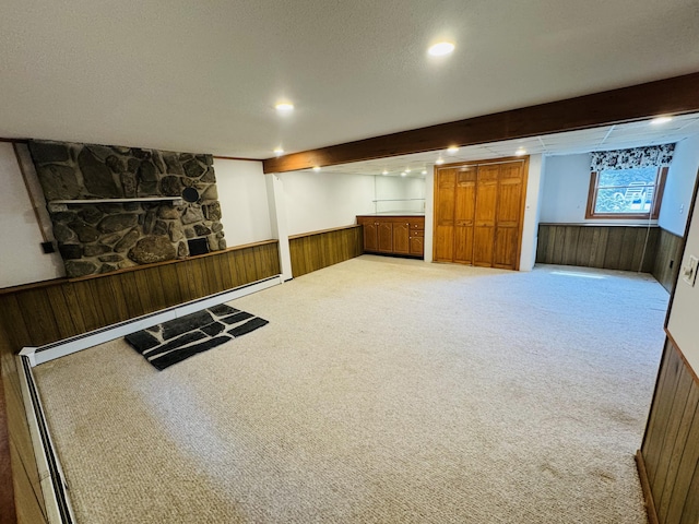 basement featuring wooden walls, wainscoting, baseboard heating, carpet floors, and recessed lighting