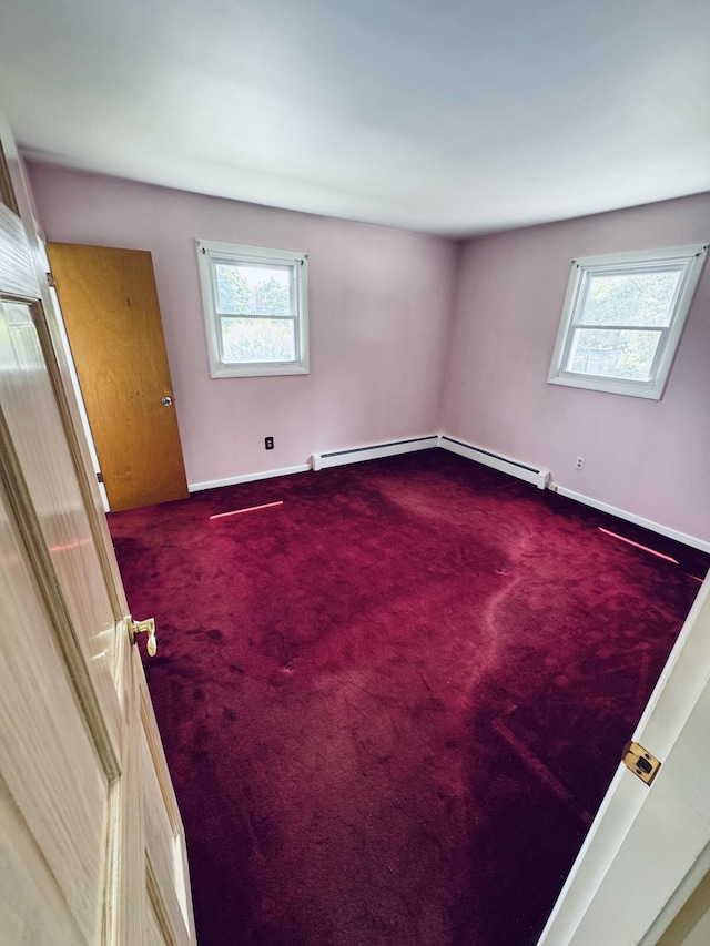 carpeted spare room featuring baseboard heating, a wealth of natural light, and baseboards