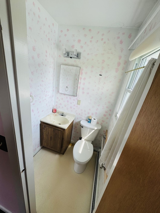 bathroom with toilet, wallpapered walls, and vanity