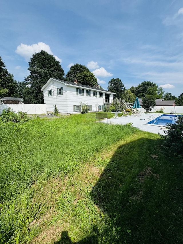 view of yard with a deck, a fenced backyard, and a fenced in pool