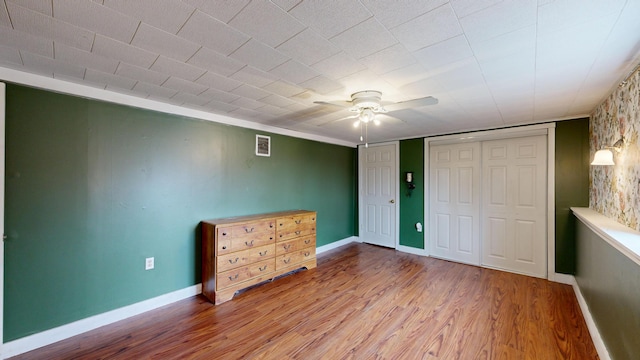 unfurnished bedroom featuring visible vents, baseboards, a ceiling fan, and wood finished floors