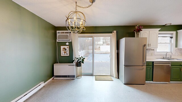 kitchen with green cabinets, a notable chandelier, a baseboard heating unit, appliances with stainless steel finishes, and a sink