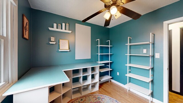 interior space featuring wood finished floors, baseboards, and a ceiling fan