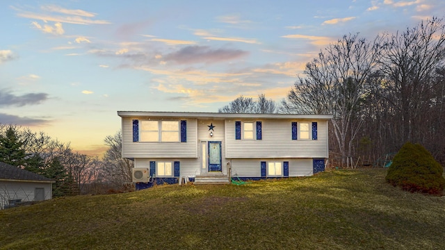 bi-level home with entry steps, a lawn, and ac unit