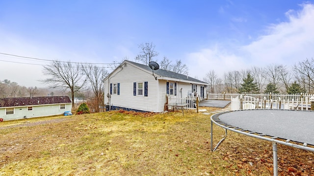 view of home's exterior with a yard, a trampoline, and a wooden deck