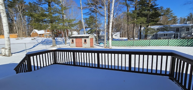 snow covered deck with an outbuilding, a storage unit, and a fenced backyard