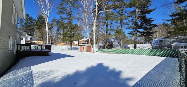 snowy yard with a wooden deck and fence