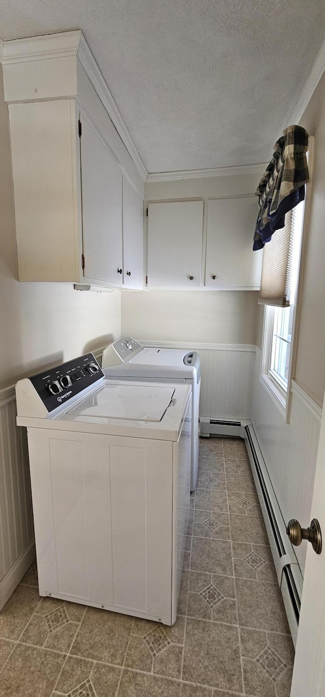 washroom with a baseboard radiator, cabinet space, wainscoting, a textured ceiling, and washer and dryer