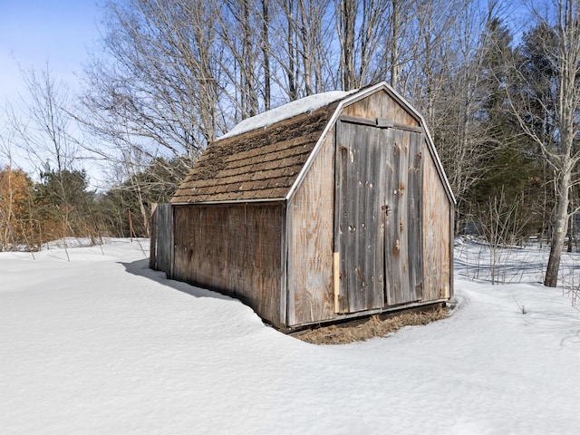 snow covered structure with a storage shed and an outdoor structure