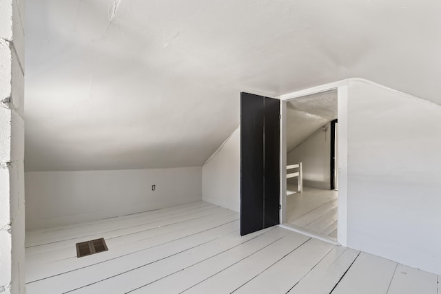 bonus room featuring light wood-style floors and vaulted ceiling