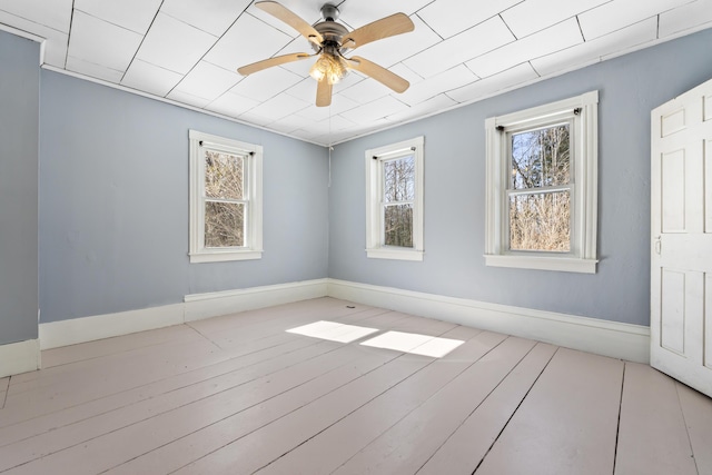 empty room featuring baseboards, ceiling fan, and wood-type flooring