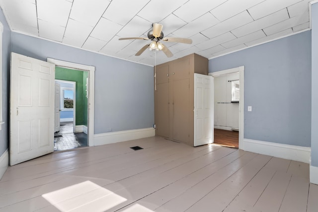 unfurnished bedroom with visible vents, baseboards, light wood-style floors, and a ceiling fan