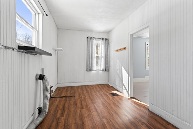 unfurnished living room featuring visible vents, baseboards, a healthy amount of sunlight, and wood finished floors