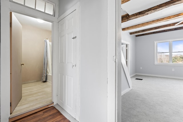 hallway featuring beam ceiling, dark wood-style floors, baseboards, and visible vents