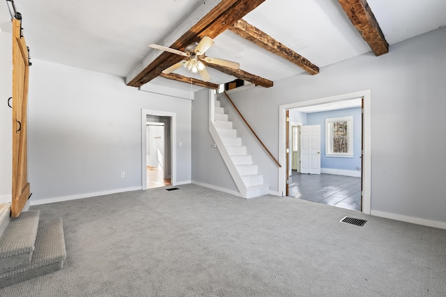 unfurnished living room featuring stairway, carpet, visible vents, beam ceiling, and a barn door