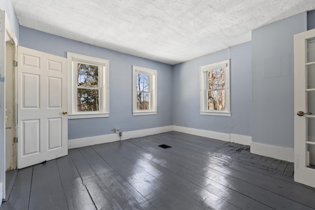 spare room with visible vents, dark wood-style floors, baseboards, and a textured ceiling