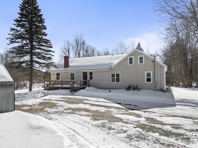 snow covered rear of property with a chimney and a wooden deck