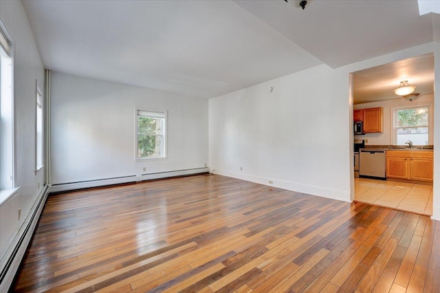 spare room featuring a baseboard heating unit, light wood finished floors, and a sink