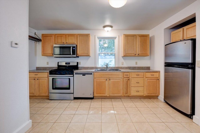 kitchen featuring light tile patterned floors, light brown cabinets, stainless steel appliances, and a sink