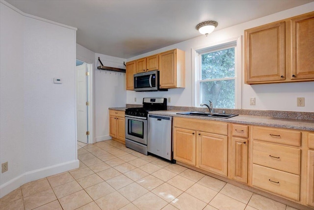 kitchen featuring appliances with stainless steel finishes, light tile patterned floors, a sink, and light brown cabinetry