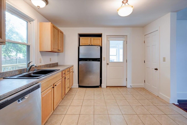 kitchen with appliances with stainless steel finishes, a healthy amount of sunlight, light brown cabinets, and a sink